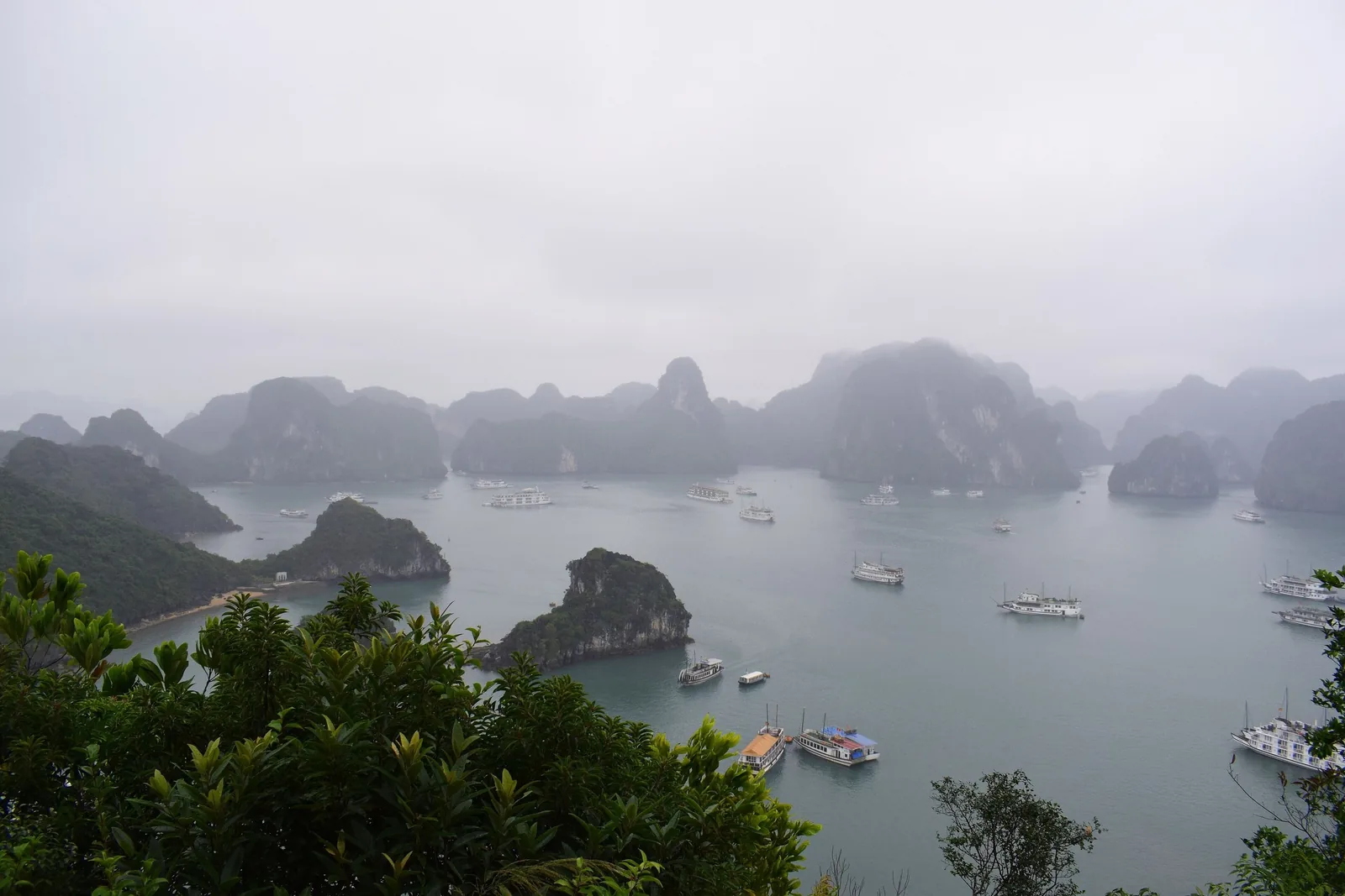 Misty limestone karsts and cruise boats seen from a viewpoint above Ha Long Bay, Vietnam.