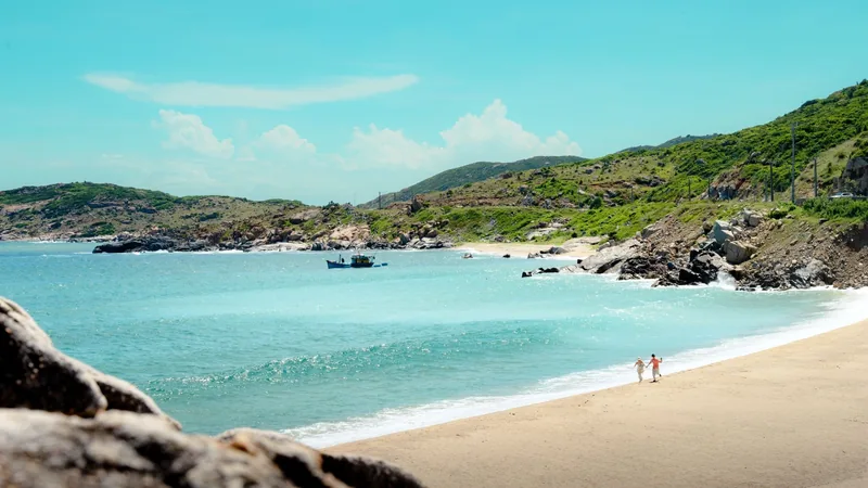 Turquoise waters and green hills frame a quiet sandy beach in Ninh Thuan.
