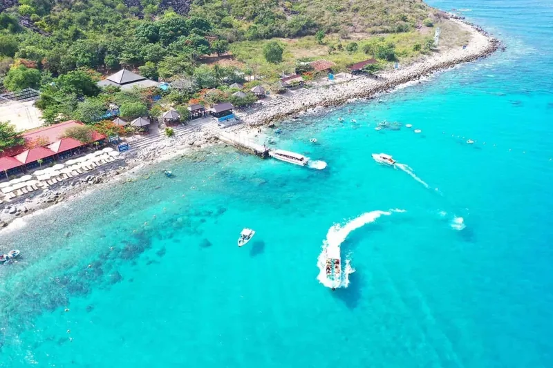 Aerial view of turquoise water, speedboats and a jetty along the rocky coast of Hon Mun island near Nha Trang.