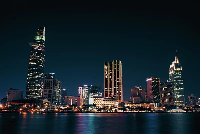Illuminated skyscrapers rise along the Saigon River waterfront at night in Ho Chi Minh City.